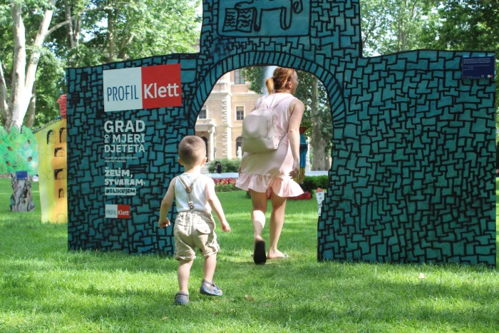 Dijete i odrasla osoba prolaze kroz instalaciju u parku